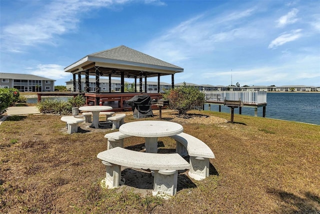 dock area with a gazebo, a water view, and a lawn