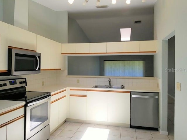 kitchen with sink, light tile patterned floors, stainless steel appliances, and a high ceiling