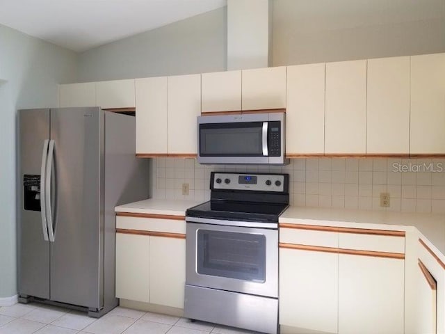 kitchen with decorative backsplash, light tile patterned floors, stainless steel appliances, and white cabinets