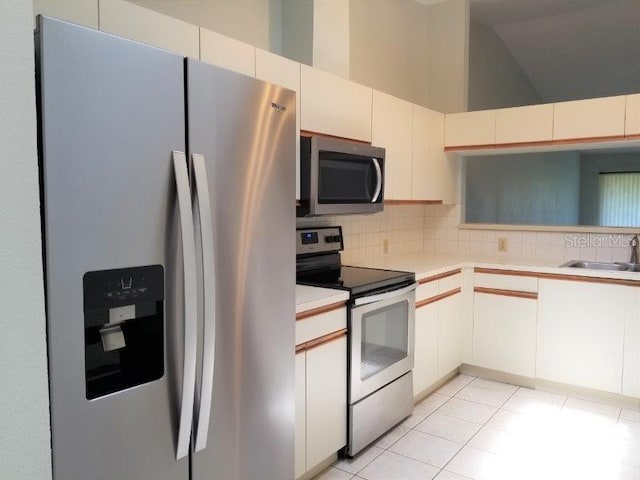 kitchen with white cabinetry, sink, stainless steel appliances, and a high ceiling