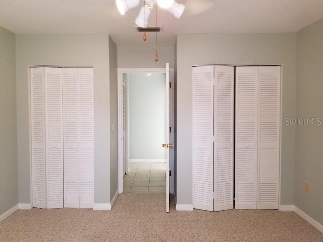 unfurnished bedroom with multiple closets, ceiling fan, and light carpet