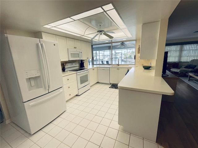 kitchen with white cabinetry, kitchen peninsula, white appliances, a tray ceiling, and light tile patterned flooring