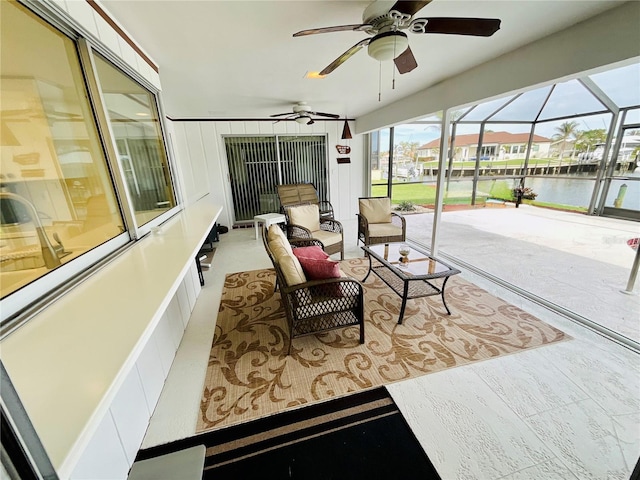 sunroom featuring ceiling fan and a water view