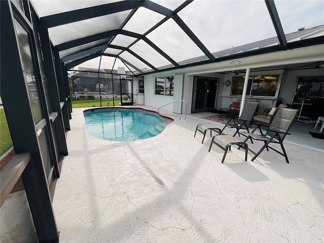 view of swimming pool with glass enclosure, a patio area, and ceiling fan