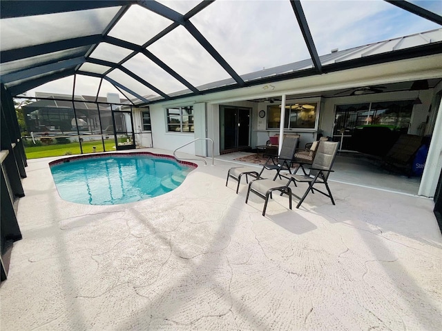 view of swimming pool featuring glass enclosure, ceiling fan, and a patio