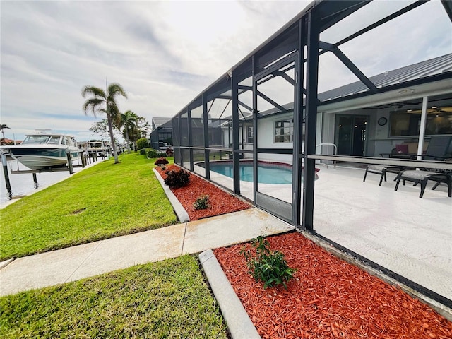 exterior space featuring a patio, a water view, glass enclosure, and a lawn