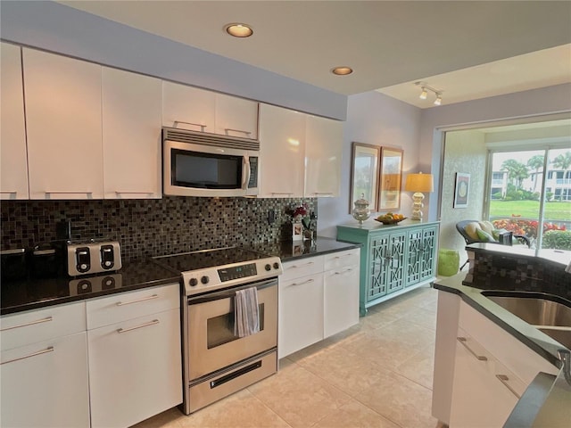 kitchen featuring decorative backsplash, stainless steel appliances, white cabinetry, and light tile patterned flooring