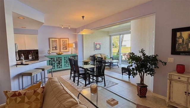 dining space with sink, light tile patterned floors, and rail lighting