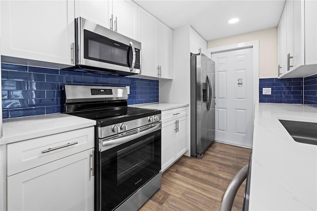 kitchen with appliances with stainless steel finishes, white cabinetry, and light stone counters