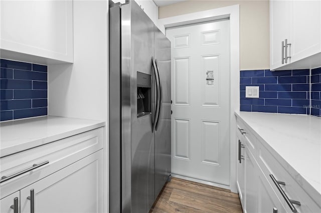 kitchen featuring stainless steel refrigerator with ice dispenser, backsplash, dark hardwood / wood-style flooring, light stone counters, and white cabinetry