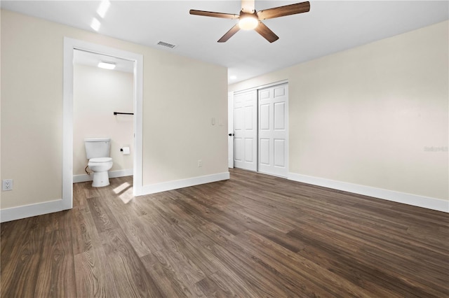 unfurnished bedroom featuring a closet, dark hardwood / wood-style flooring, ensuite bathroom, and ceiling fan