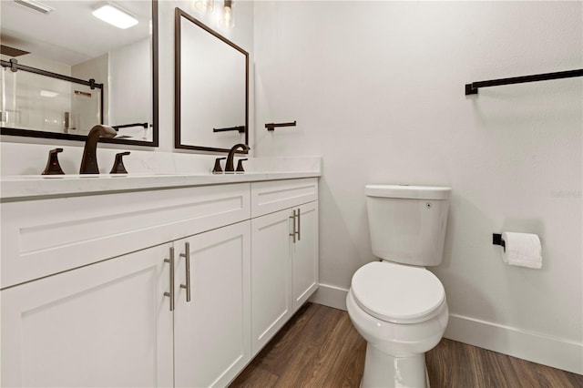 bathroom featuring toilet, vanity, a shower with shower door, and hardwood / wood-style flooring