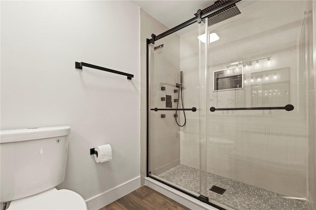 bathroom featuring toilet, a shower with door, and hardwood / wood-style flooring