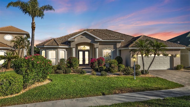 mediterranean / spanish house featuring french doors, a garage, and a lawn