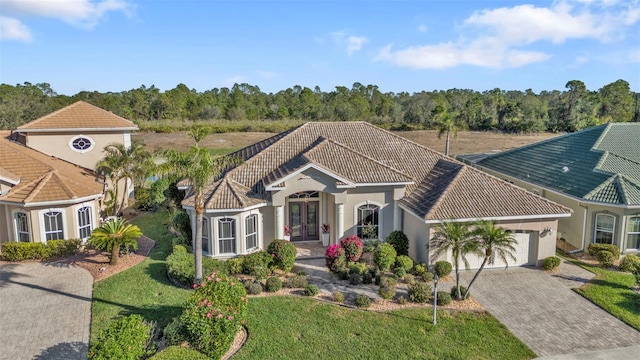 mediterranean / spanish home with french doors, a front lawn, and a garage