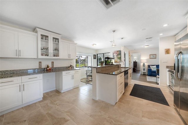 kitchen with sink, hanging light fixtures, stainless steel appliances, dark stone countertops, and white cabinets