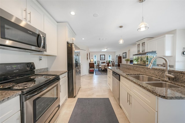 kitchen with stainless steel appliances, sink, decorative light fixtures, dark stone countertops, and white cabinetry