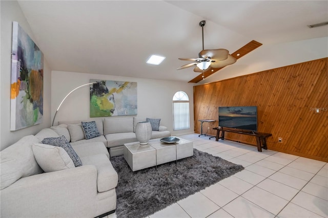 tiled living room with ceiling fan, wood walls, and vaulted ceiling