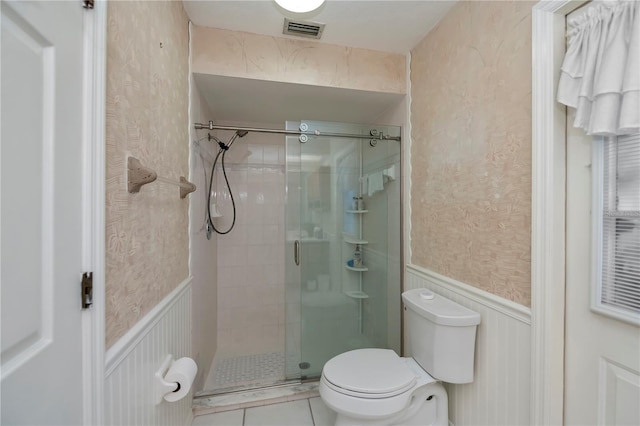 bathroom with tile patterned floors, toilet, and a shower with shower door