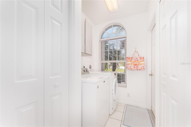 laundry room featuring washing machine and clothes dryer, light tile patterned floors, and cabinets