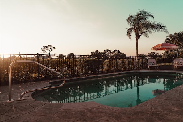 pool at dusk with a patio area