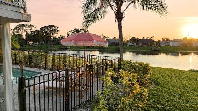 pool at dusk with a lawn and a water view