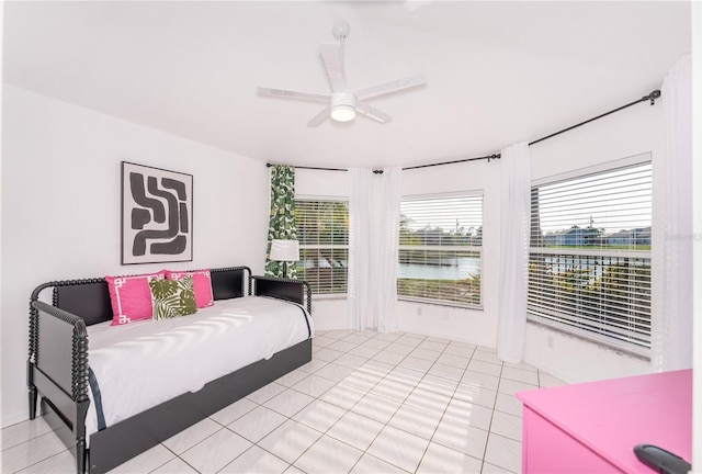 bedroom with ceiling fan, a water view, and light tile patterned floors