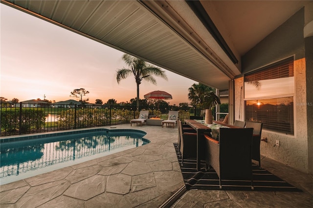 pool at dusk with a patio area