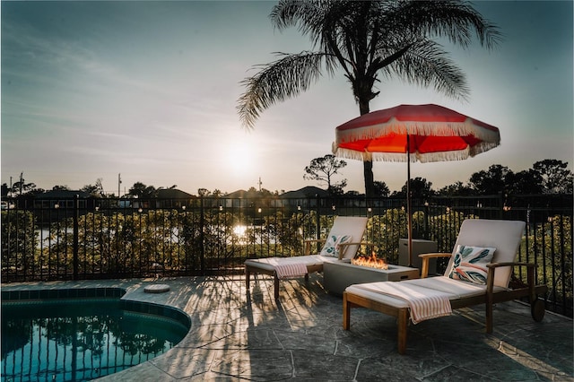 pool at dusk featuring a fire pit and a patio area