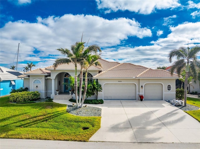 mediterranean / spanish home featuring a garage and a front yard