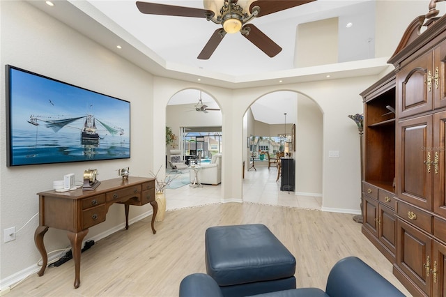 interior space with ceiling fan, light hardwood / wood-style flooring, and a high ceiling