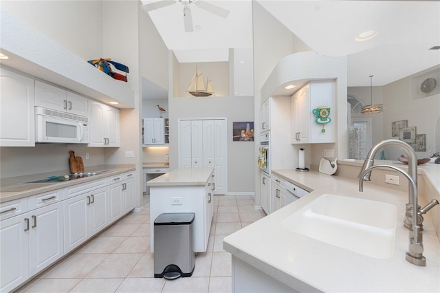 kitchen with sink, decorative light fixtures, stovetop, a center island, and white cabinetry