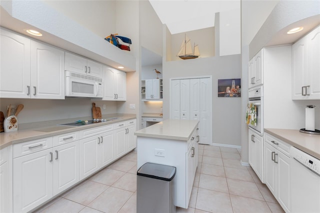 kitchen featuring white cabinets, a kitchen island, white appliances, and light tile patterned floors