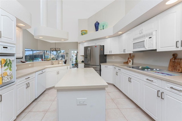 kitchen featuring a center island, white appliances, a high ceiling, white cabinets, and sink