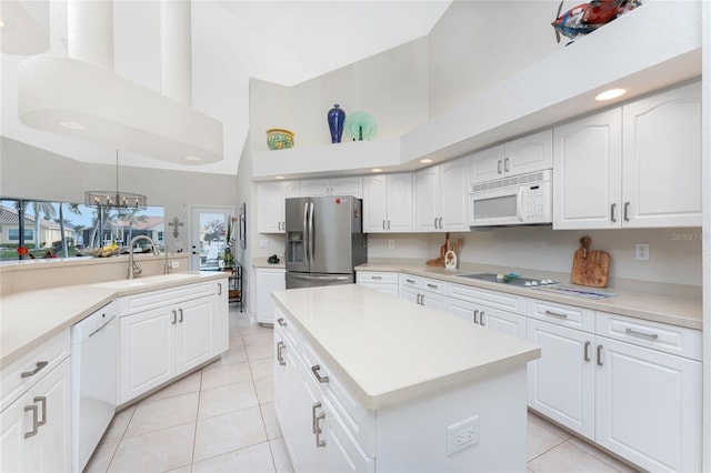 kitchen with a center island, white cabinets, decorative light fixtures, and white appliances