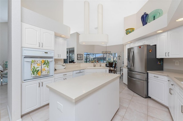 kitchen featuring kitchen peninsula, white cabinetry, a high ceiling, and white appliances