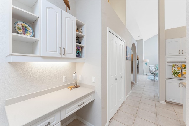 hallway with lofted ceiling and light tile patterned floors