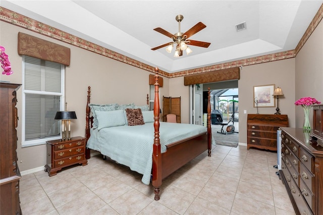 bedroom featuring access to exterior, a raised ceiling, ceiling fan, and light tile patterned flooring