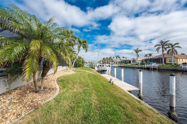 view of dock with a lawn and a water view