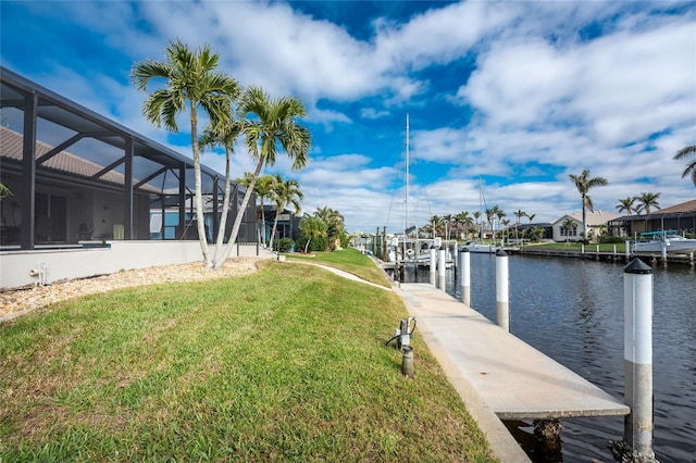 dock area with a yard, a water view, and glass enclosure