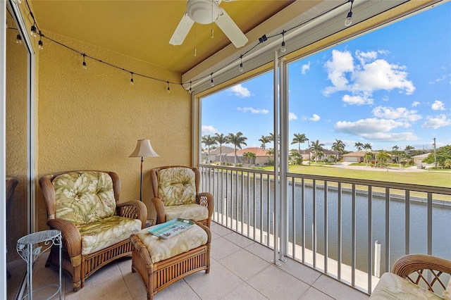 sunroom / solarium featuring ceiling fan and a water view