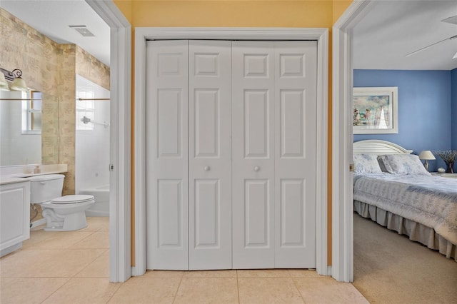 tiled bedroom featuring ensuite bath and a closet