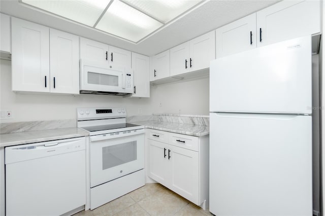 kitchen featuring white cabinets, light tile patterned flooring, light stone countertops, and white appliances