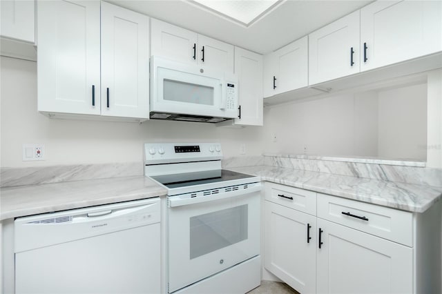 kitchen with white cabinetry, light stone countertops, and white appliances