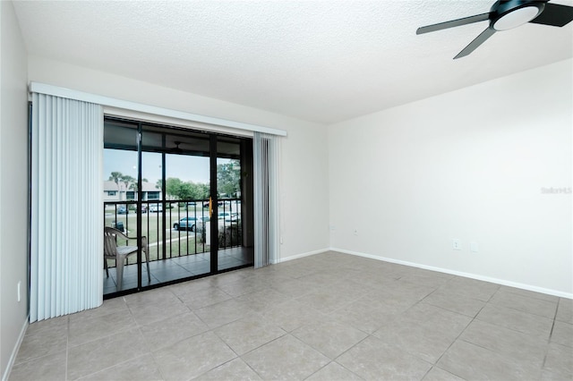 spare room featuring ceiling fan, light tile patterned floors, and a textured ceiling