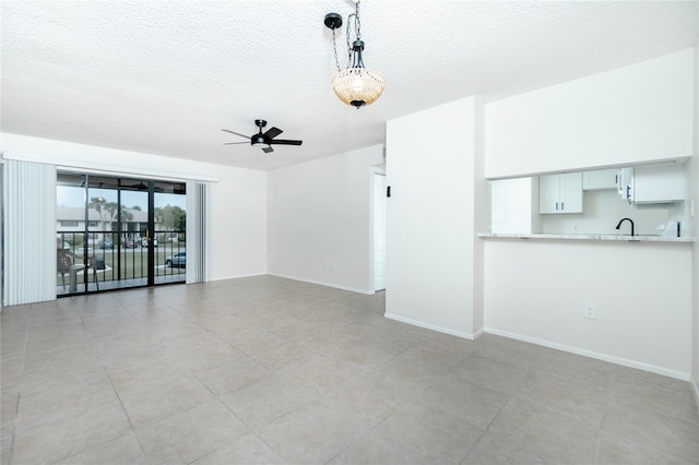 unfurnished living room with ceiling fan, sink, and a textured ceiling