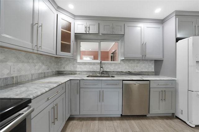 kitchen featuring sink, dishwasher, light stone counters, white refrigerator, and gray cabinets