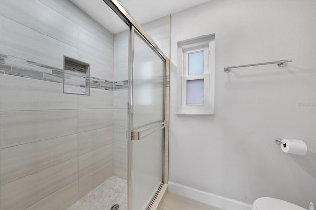 bathroom featuring toilet and a shower with door