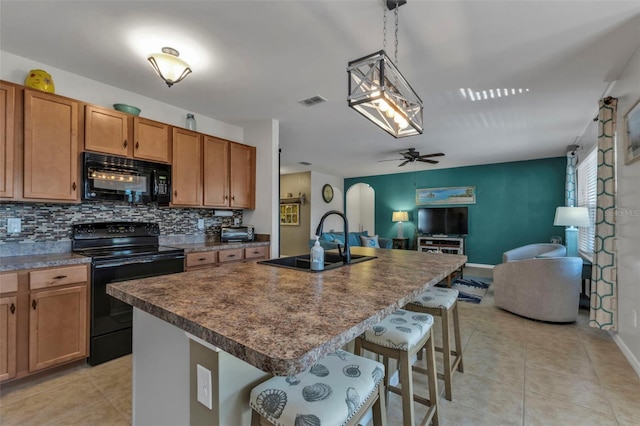 kitchen featuring a kitchen bar, sink, black appliances, and an island with sink