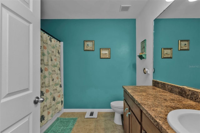 bathroom with toilet, vanity, and tile patterned flooring